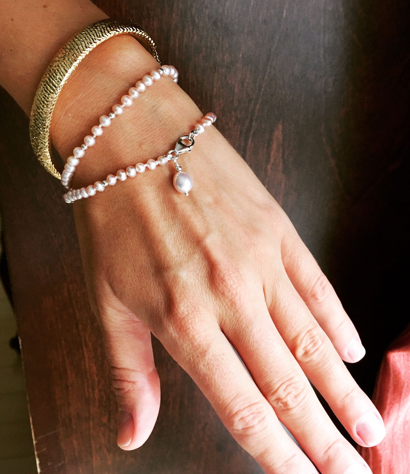 Dainty pearl bracelet with pearl charm features lustrous small pink pearls and a dangling pink pearl charm
